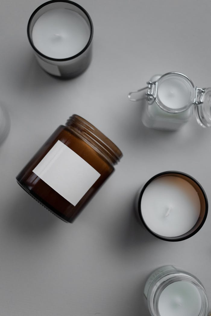 Flat lay of assorted candles in glass containers featuring a blank label for branding mockup.